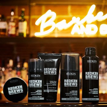 Redken Brews haircare and styling products on bar with neon light in background