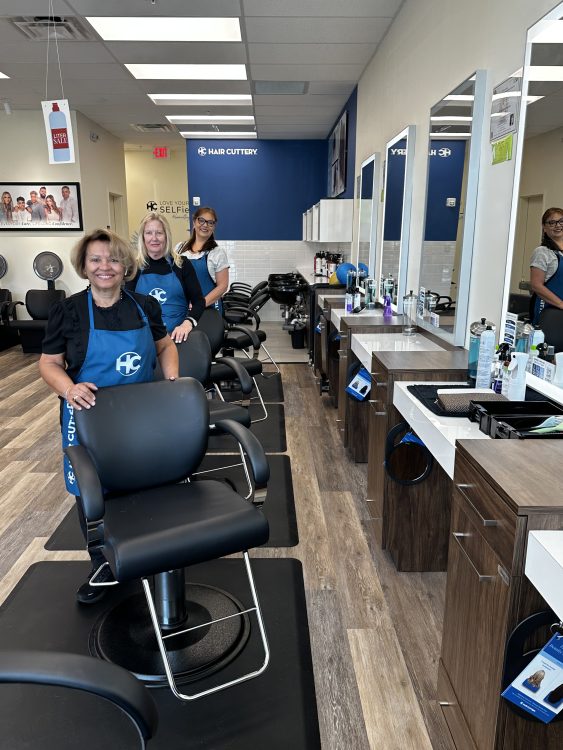 Hair Cuttery stylists standing behind salon chairs.